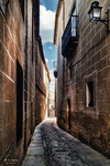 Callejón estrecho y oscuro entre muros de piedra en Cáceres.