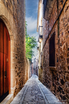 Calle estrecha con puerta roja y muros antiguos en Cáceres.