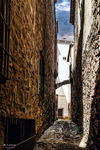Callejuela estrecha entre muros altos y casas antiguas de Cáceres.