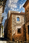 Fachada de piedra con ventana bajo cielo azul en Cáceres.