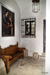 Interior histórico con banco, cuadro y reja en una estancia de Cáceres.