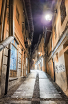 Calle estrecha iluminada de noche entre edificios antiguos de León.