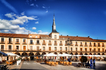 Plaza Mayor de León con torre y soportales bajo cielo intenso.