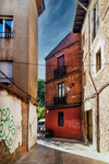 Rincón estrecho con fachada roja y muros antiguos en León.