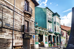Calle urbana con fachadas históricas y edificio verde en León.