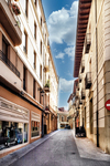 Calle estrecha con comercios y edificios altos en el centro de León.