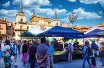 Plaza Mayor de León con puestos de mercado y cielo azul.