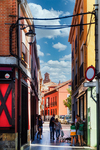 Calle estrecha con fachadas de colores y cielo azul en León.