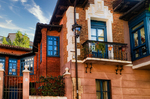 Casa de ladrillo con balcones acristalados en una calle de León.