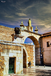 Arco de piedra con escudos en un edificio histórico de León.