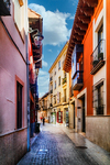 Calle estrecha con fachadas cálidas y suelo empedrado en León.