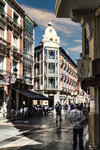 Calle céntrica de León con edificios altos y gente paseando.
