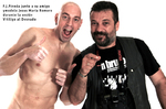 Dos hombres posando en estudio, uno de ellos señalando hacia la cámara.