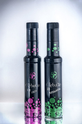 Bodegón de dos botellas negras con diseño floral rosa y verde sobre fondo claro.