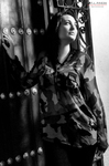 Eva posa en blanco y negro junto a una puerta, con blusa estampada y gesto elegante.
