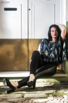 Eva sentada en un interior claro, con blusa azul estampada y pantalón negro.