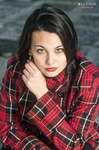 Retrato de Eva con camisa roja de cuadros, apoyada sobre los brazos y mirada intensa.