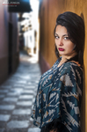 Eva posa de perfil en un pasillo estrecho, con blusa estampada y labios rojos.
