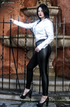 Eva de cuerpo entero junto a una barandilla, con camisa blanca, pantalón negro y tacones.