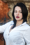 Retrato de Eva con camisa blanca y labios rojos, junto a una pared de tonos cálidos.
