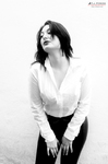 Eva posa en blanco y negro con camisa blanca, inclinada hacia delante y mirada elevada.
