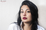 Retrato cercano de Eva con camisa blanca, labios rojos y fondo claro.