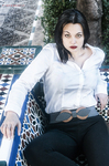 Eva sentada en un banco de azulejos, con camisa blanca y mirada directa.