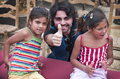 Tres niños posan sonrientes junto a una integrante del proyecto Caravan durante una jornada cultural.