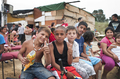 Niños y adultos sentados como público en una representación callejera de la compañía italiana Caravan.