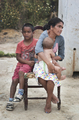 Mujer con una niña en brazos durante una actividad comunitaria de la compañía italiana Caravan.