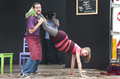 Actor sostiene a una actriz en una pose acrobática durante una escena teatral.