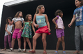 Niñas participantes actúan sobre el escenario en una actividad teatral comunitaria.