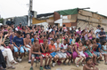 Niños, familias y artistas posan juntos en una actividad comunitaria de la compañía Caravan.
