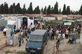 Vista general del barrio con vehículos, escenario móvil y público durante el proyecto Caravan.