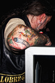 Hombre tatuado visto de espaldas con chaleco motero y tatuajes en el brazo.