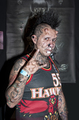 Hombre tatuado con camiseta sin mangas posa con gesto intenso en ambiente motero.