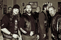 Grupo de moteros con chalecos posa en una fotografía de estética rockera.