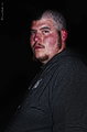 Retrato de un hombre iluminado con luz intensa sobre fondo negro en la serie Motos y tatuajes.