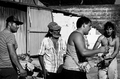Grupo de personas en blanco y negro caminando por una calle del asentamiento de El Vacie.