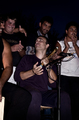 Personas cantando o participando en una reunión comunitaria dentro de la serie Asina.