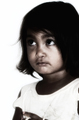 Primer plano de una niña con mirada seria sobre fondo claro en el asentamiento de El Vacie.