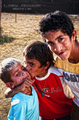 Hombre sonriente con dos niños en una escena familiar del asentamiento.