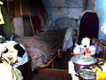 Interior de una vivienda precaria con utensilios domésticos y objetos cotidianos.