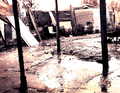 Calle anegada y vallado en una escena de lluvia o barro en el asentamiento chabolista de El Vacie.