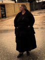 Mujer mayor vestida de oscuro camina por una calle del asentamiento chabolista de El Vacie.