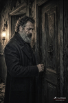 Hombre con barba frente a una puerta antigua en una escena oscura de la serie Las puertas cerradas.