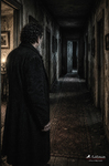 Figura masculina al fondo de un pasillo oscuro con puertas cerradas.