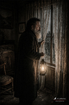 Hombre junto a una puerta antigua en una habitación deteriorada e iluminada tenuemente.