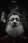 Retrato desde ángulo bajo de un hombre barbado en una habitación oscura con un reloj al fondo, perteneciente a La Grieta de F. J. Pineda.