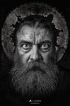 Retrato oscuro de un hombre con barba, mirada frontal y un círculo agrietado alrededor de la cabeza, de la serie La Grieta de F. J. Pineda.